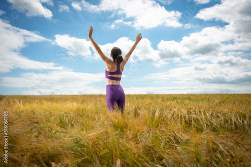 Woman with her arms raised in the middle of a field enjoying the summer and nature