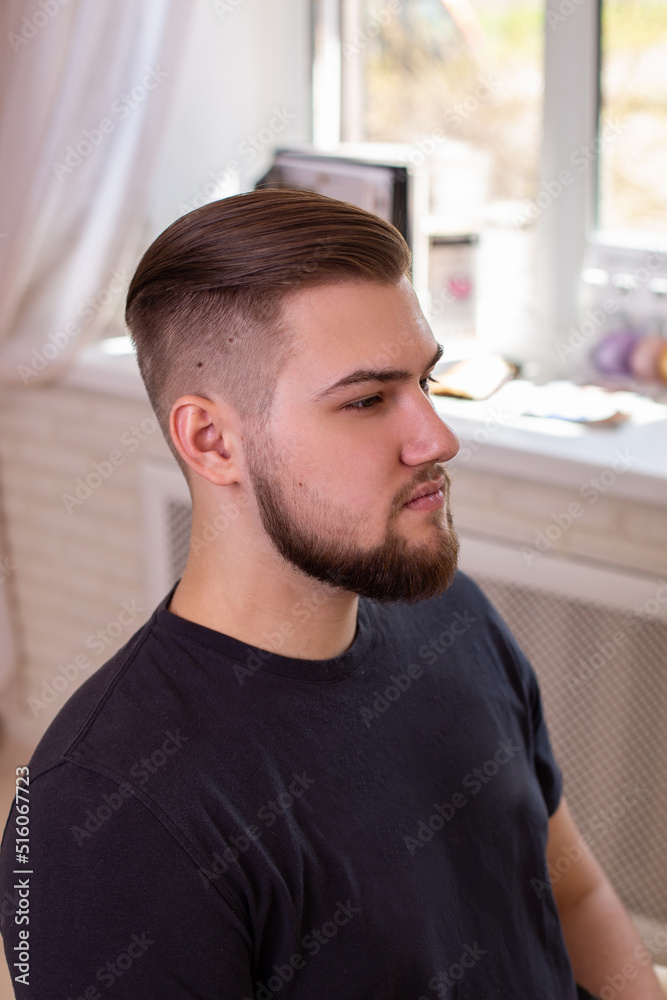 Obraz premium Brunette man with stylish haircut on barbershop background 