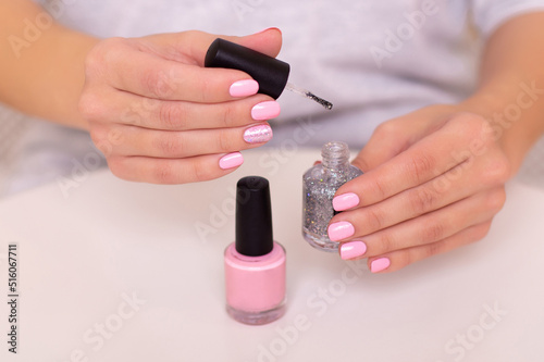 Beautiful female hands with pink manicure nails holding silver colored gel polish 