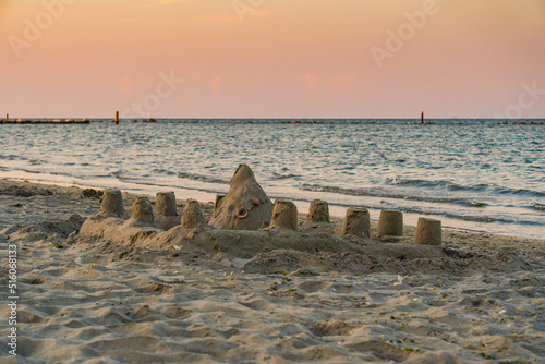 Scena al mare con dei castelli di sabbia costruiti sulla sabbia, al tramonto, in estate, in Italia. Vacanze. Viaggiare. Sera. photo