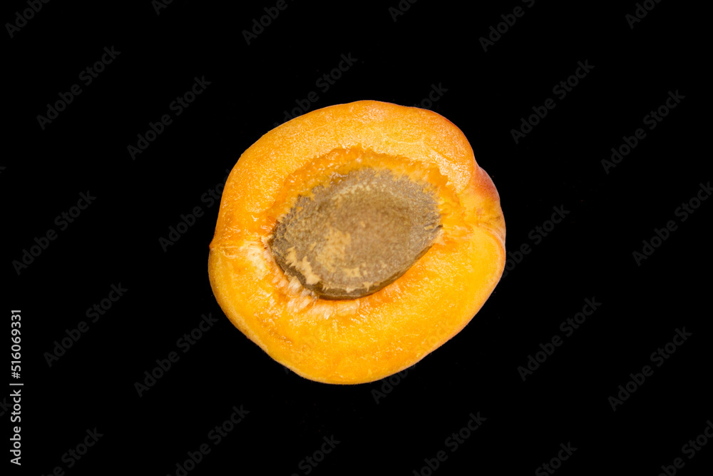 half an apricot with a stone is lying on a black background half an apricot with a stone is lying on a black background