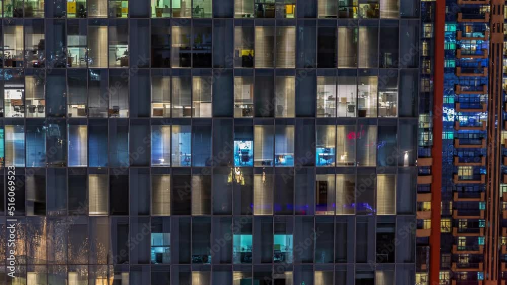 Night aerial view of office building glass window facade with illuminated lighted workspace rooms timelapse. Glowing and flashing light in skyscraper Night aerial view of office building glass window facade with illuminated lighted workspace rooms timelapse. Glowing and flashing light in skyscraper