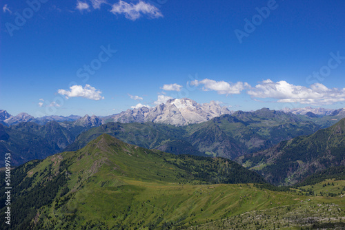 Mountain summer landscape. Grassy meadows and rocks under the blue sky. Marmolada glacier, Italy. Climate change concept. High quality image. © JulyLo.Studio
