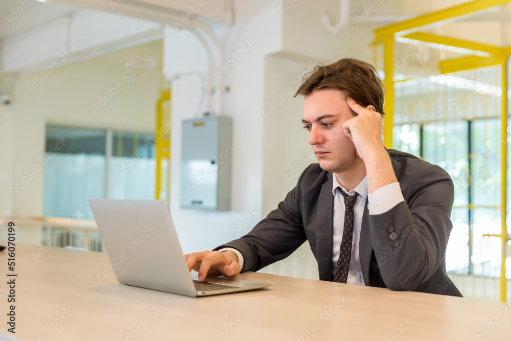 Handsome businessman working on laptop in bright modern office Handsome businessman working on laptop in bright modern office