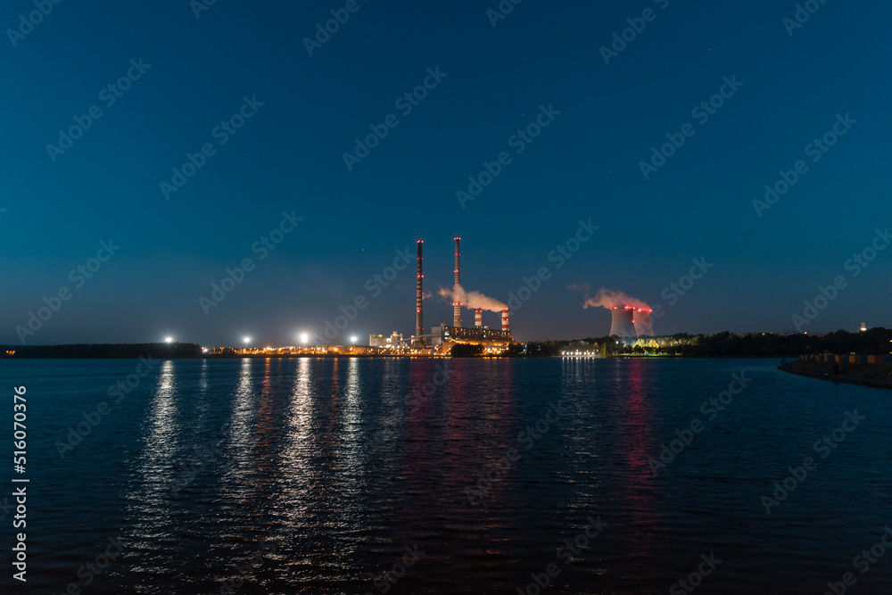 A night view of the lake, in the distance the illuminated chimneys of a coal-fired power plant.
