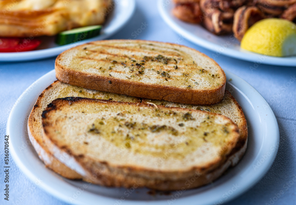 Crisp, toasted bread with drops of olive oil and herbs on a plate. Greek cuisine