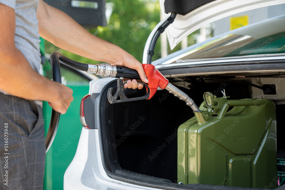 A young man pours gasoline into the gas tank of a white car.A young man pumps gasoline into a gas tank. Fuel and oil crisis. The concept of gasoline prices and the oil crisis. A young man pours gasoline into the gas tank of a white car.A young man pumps gasoline into a gas tank. Fuel and oil crisis. The concept of gasoline prices and the oil crisis.