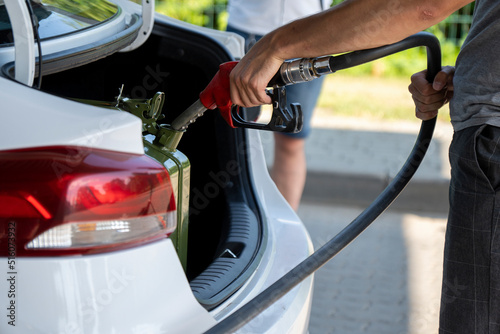 A young man pours gasoline into the gas tank of a white car.A young man pumps gasoline into a gas tank. Fuel and oil crisis. The concept of gasoline prices and the oil crisis.