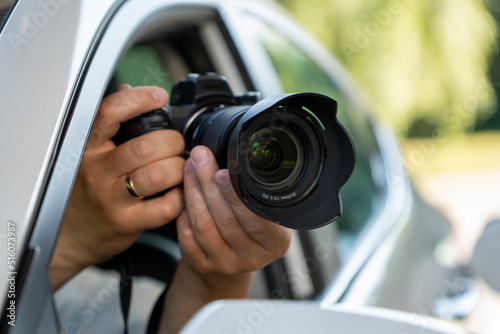 A paparazzi sits in his car and takes pictures of a famous person. Spy with camera in the car. A private detective, sitting inside the car, taking pictures with the camera.