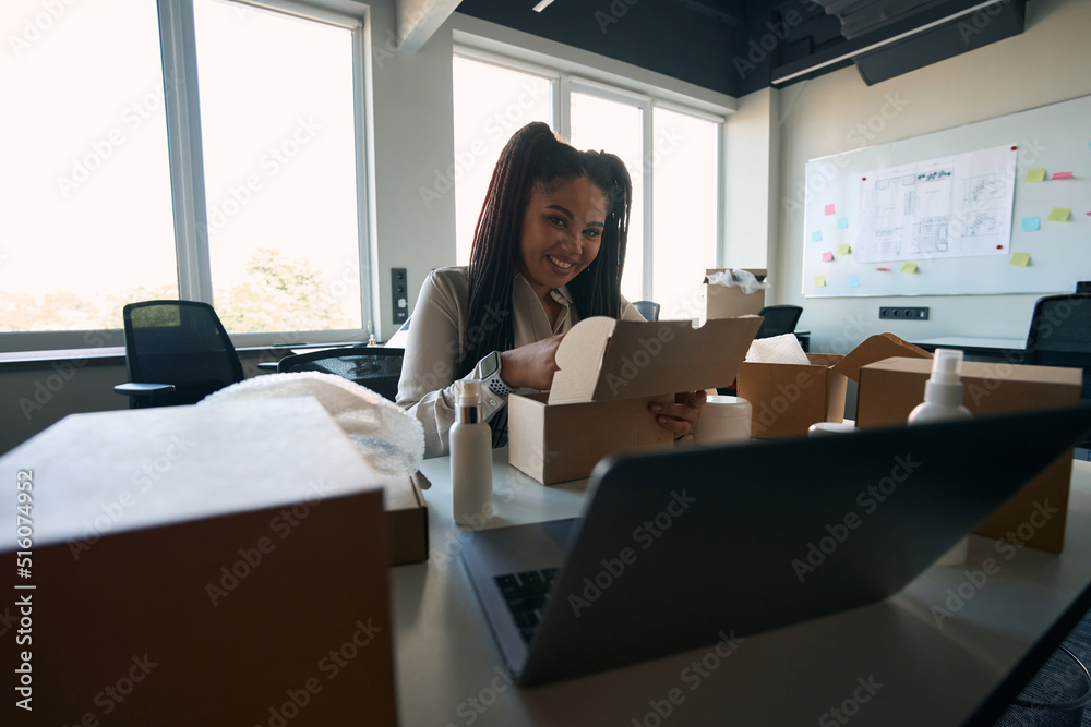 Internet shop employee placing merchandise into cardboard box Internet shop employee placing merchandise into cardboard box