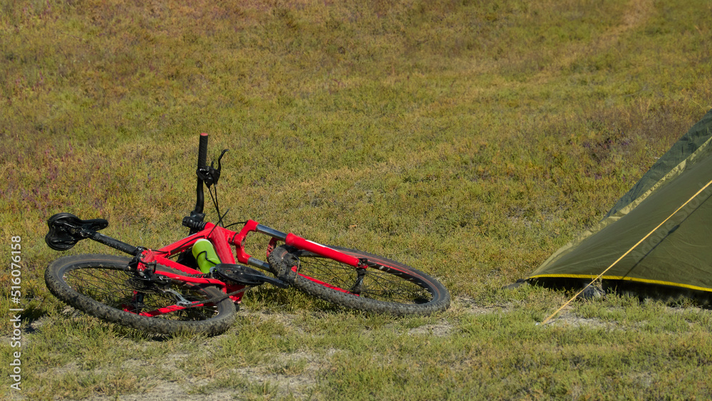 Cycling. A fragment of a tourist tent with a red bicycle lying next to it. Copy space. Cycling. A fragment of a tourist tent with a red bicycle lying next to it. Copy space.
