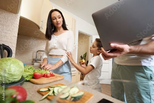 Fotografie Mother cooking in kitchen getting distracted by husband and son