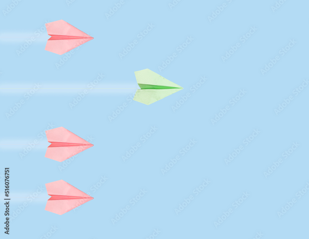 Outstanding green origami plane flying ahead of pink ones on blue sky background. Leadership, creativity concept. Victory in competition. High quality photo Outstanding green origami plane flying ahead of pink ones on blue sky background. Leadership, creativity concept. Victory in competition. High quality photo