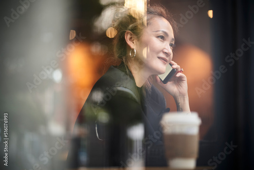 asian woman talking on cellphone in coffee shop