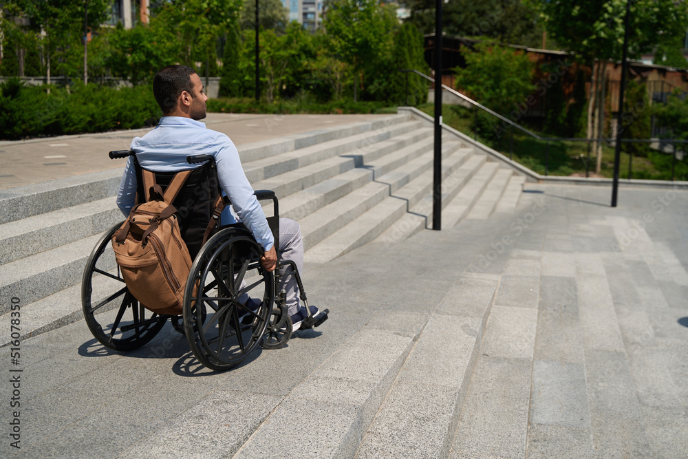 Obraz premium Man seated in manual wheel chair descending staircase