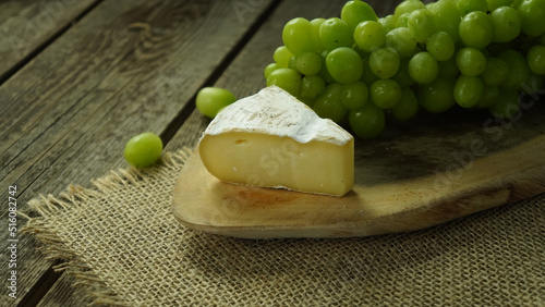 rustic cheese and green grapes on a wooden table in a farm