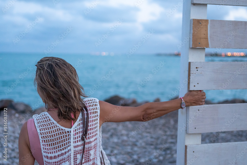 Fototapeta premium Mujer mirando el horizonte disfrutauna tarde en la playa