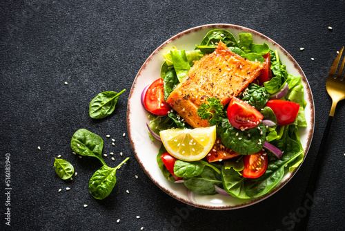 Green salad with salmon fillet. Healthy lunch, diet nutrition. Top view on black.