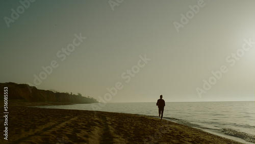 Silhouette jogger woman training on sandy beach. Sportswoman running seacoast.