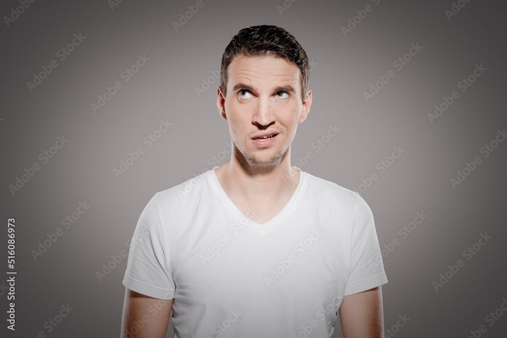 irritated and doltish man with nonsensical face expression look at top corner and show his confused emotions irritated and doltish man with nonsensical face expression look at top corner and show his confused emotions