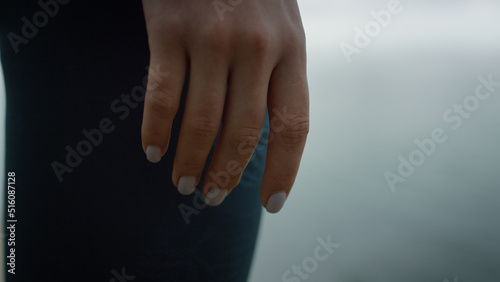 Closeup fit woman hand on calm sea view. Girl standing hill on morning. 