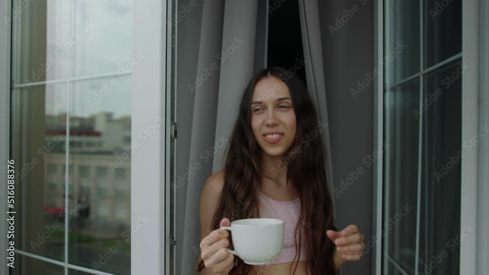 Portrait of a brunette who goes out on the balcony with a mug of morning coffee Portrait of a brunette who goes out on the balcony with a mug of morning coffee