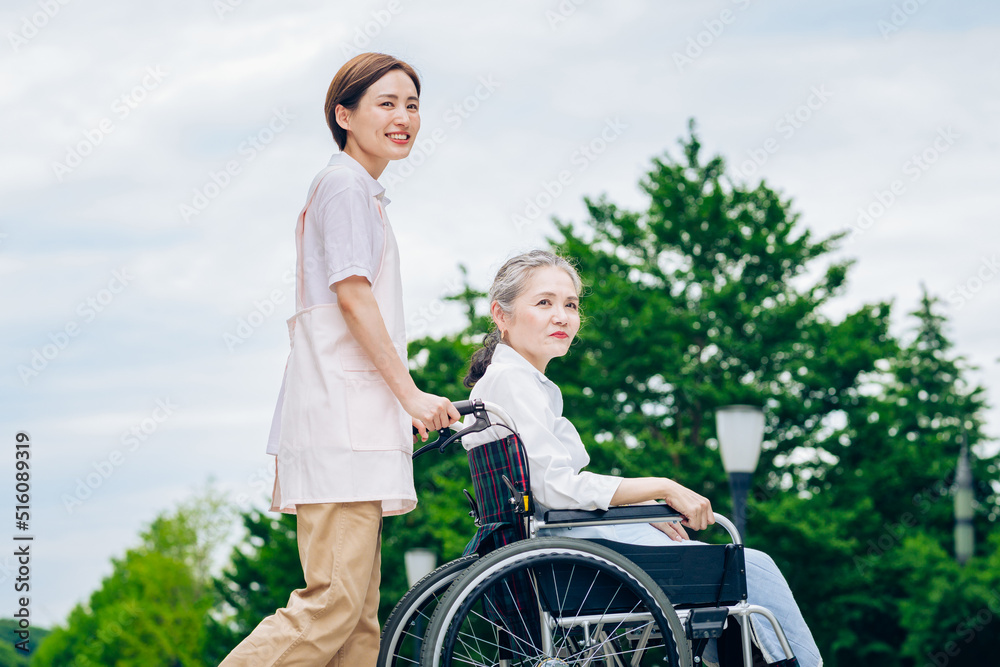 車椅子の女性と介護するエプロン姿の女性 車椅子の女性と介護するエプロン姿の女性