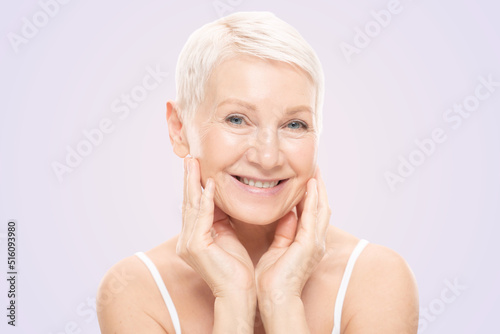 Beauty face portrait of cute and pretty senior woman with perfect fresh skin, isolated on pink