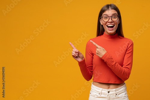 Excited young woman pointing with fingers to the side, showing unbelievable copy space for offer