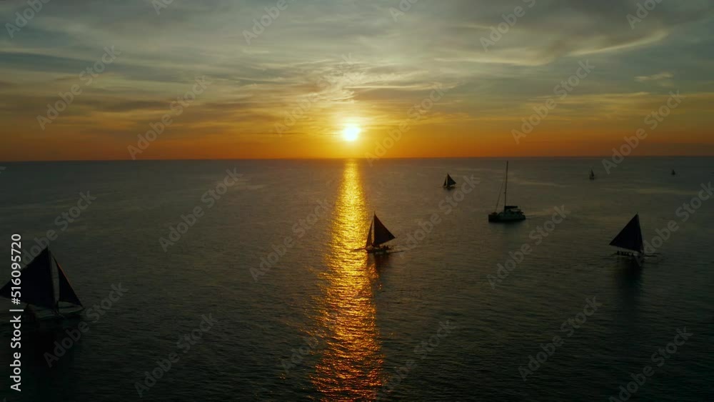 Colorful sunset above the sea surface with sail boats, aerial view Boracay, Philippines. Reflected sun on a water surface. Sunset over ocean. Seascape, Summer and travel vacation concept Colorful sunset above the sea surface with sail boats, aerial view Boracay, Philippines. Reflected sun on a water surface. Sunset over ocean. Seascape, Summer and travel vacation concept