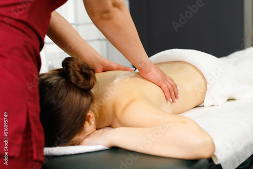 Female enjoying relaxing back massage in cosmetology spa centre, body skin care and wellness concept.