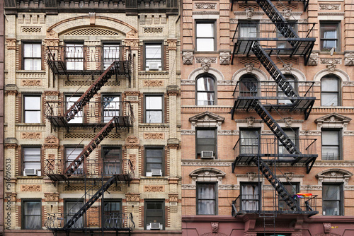 Old fashioned Manhattan apartment building facade with ornate decorative stone carving and external fire escape ladders