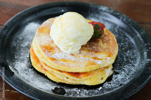 Closeup portrait of sweet pancakes with vanilla ice cream on top served in a plate photo