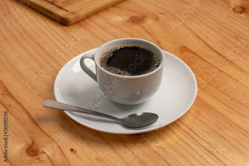 A cup of black coffee with a spoon in a cafeteria