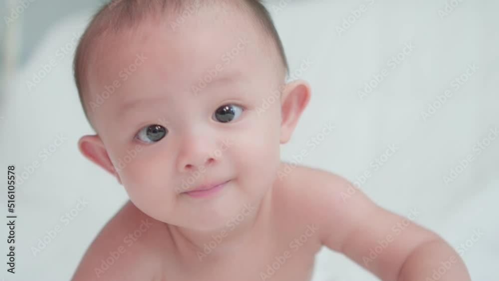 Close-up of face cute asian newborn baby. while playing and crawling on white bed look at camera with laughing smile happy face. Innocent little new infant adorable. Parenthood and Mother Day concept Close-up of face cute asian newborn baby. while playing and crawling on white bed look at camera with laughing smile happy face. Innocent little new infant adorable. Parenthood and Mother Day concept