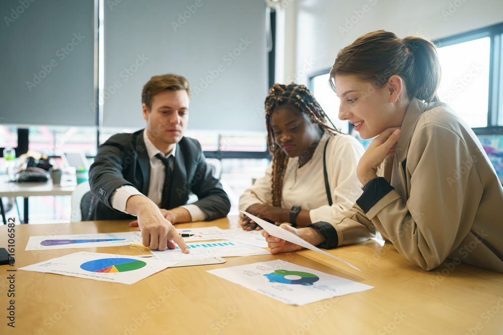 Image of young business people discussing document in paperwork data on desk at meeting Image of young business people discussing document in paperwork data on desk at meeting