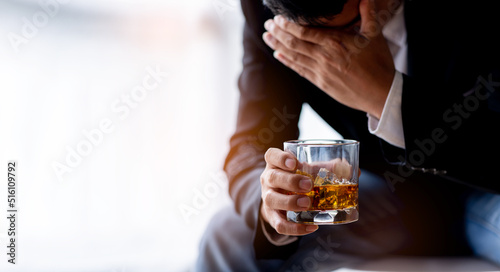 Close up of Asian businessman hold a glass of whiskey in hand with stressed depressed and sad when facing financial or family problems
