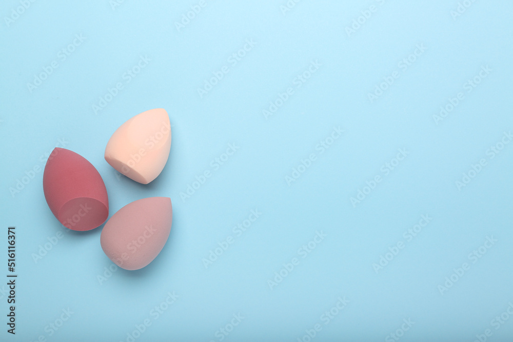 makeup sponges  on blue background. Beauty concept, top view, space for text