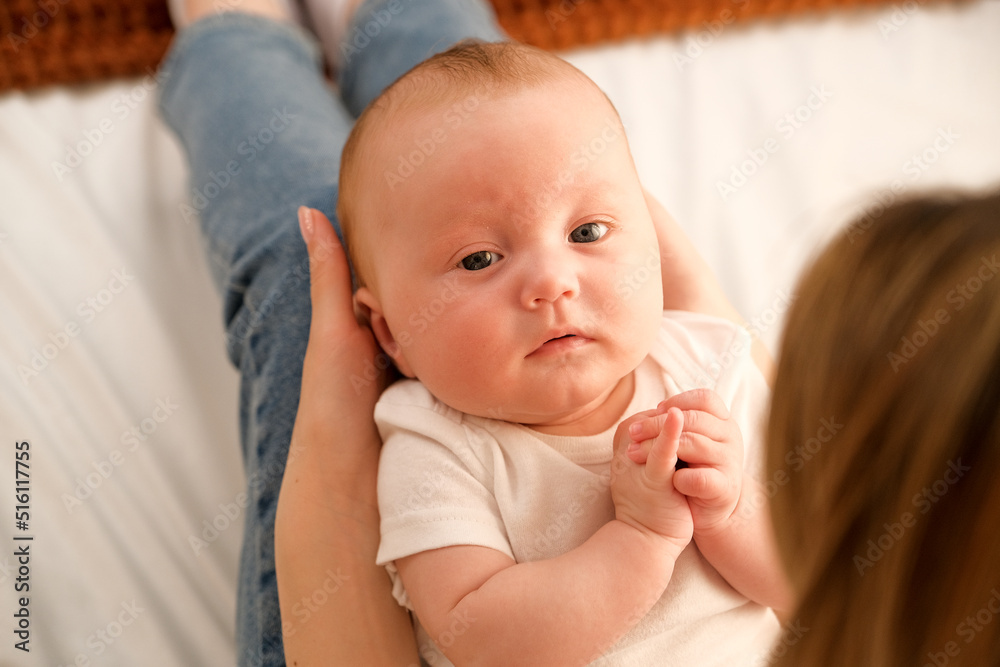 mom holds a newborn baby in her arms. in the background the sun shines from the window. mom holds a newborn baby in her arms. in the background the sun shines from the window.