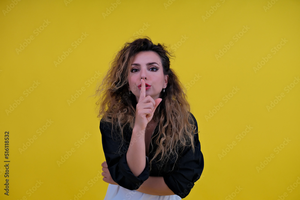 Close-up portrait beautiful girl on a yellow background. woman showing finger silence, girl showing shh sign keep secret Close-up portrait beautiful girl on a yellow background. woman showing finger silence, girl showing shh sign keep secret