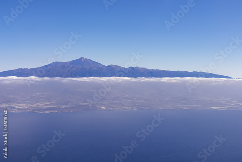 Window view from an airplane on the volcano mountain peak of Pico del Teide on Tenerife, Canary Islands, Spain, Europe, EU. High peak are shrouded in clouds. Flying high above the ground. Freedom © Chris