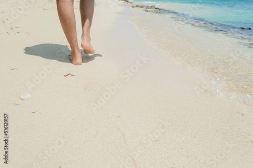 Pies femeninos caminando en una hermosa playa aislada. Huellas en la arena de la playa