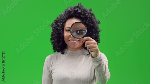 african american woman smiling looking through a magnifying glass Isolated on Green Screen
