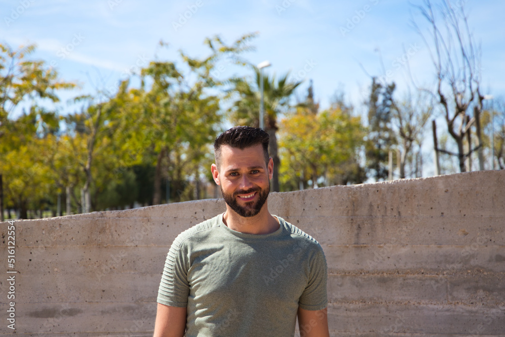 Handsome young man with blue eyes is standing on the stairs leading down to the river in the park. The man is on holiday in a European city. Travel and holiday concept. Handsome young man with blue eyes is standing on the stairs leading down to the river in the park. The man is on holiday in a European city. Travel and holiday concept.