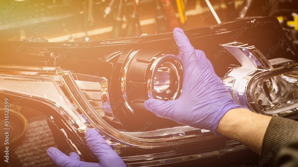 Car headlight in repair closeup. The car mechanic installs the lens in