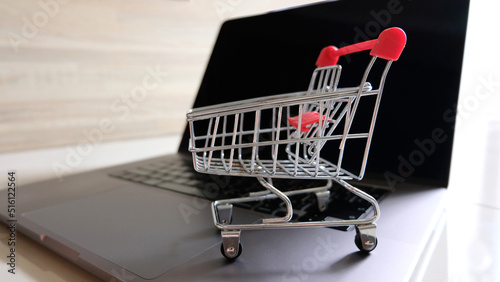 Online shopping concept. Shopping cart, laptop on the desk.