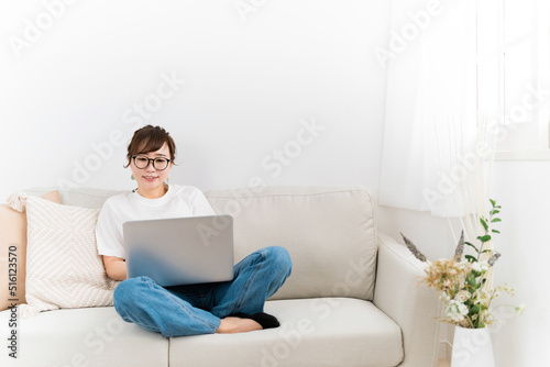 家のソファでパソコンを使う日本人女性 