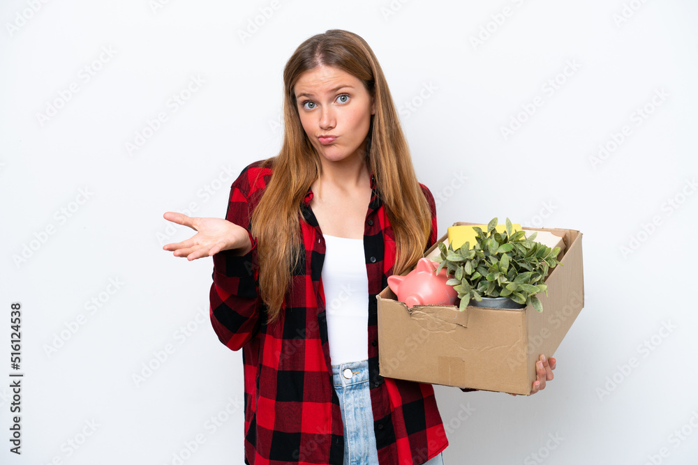 Young caucasian woman making a move while picking up a box full of things isolated on white background having doubts while raising hands Young caucasian woman making a move while picking up a box full of things isolated on white background having doubts while raising hands