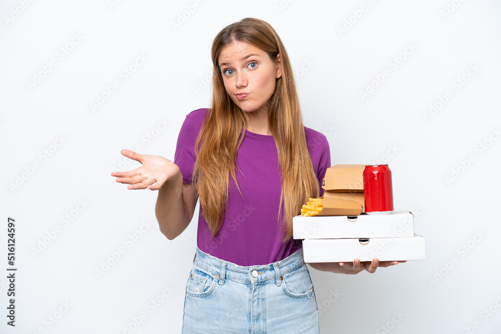 Young pretty blonde woman holding fast food isolated on white background having doubts while raising hands Young pretty blonde woman holding fast food isolated on white background having doubts while raising hands