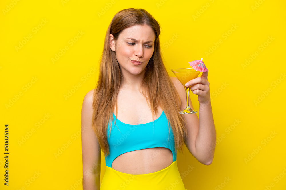 Young caucasian woman holding a cocktail isolated on yellow background with sad expression Young caucasian woman holding a cocktail isolated on yellow background with sad expression